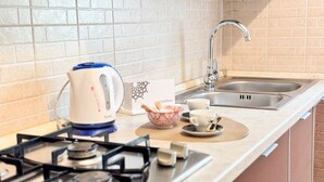 Una cucina con piano cottura a gas, bollitore, lavello e una ciotola di pane.