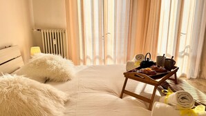 A neatly made bed with fluffy pillows, a tray with breakfast items, and a rolled towel on the floor. - Casa Dora in Chioggia (Chioggia)
