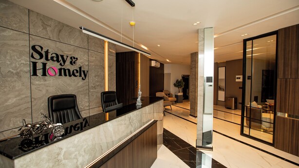 A reception area with a marble counter, two black chairs, and a sign that reads "Stay & Homely."