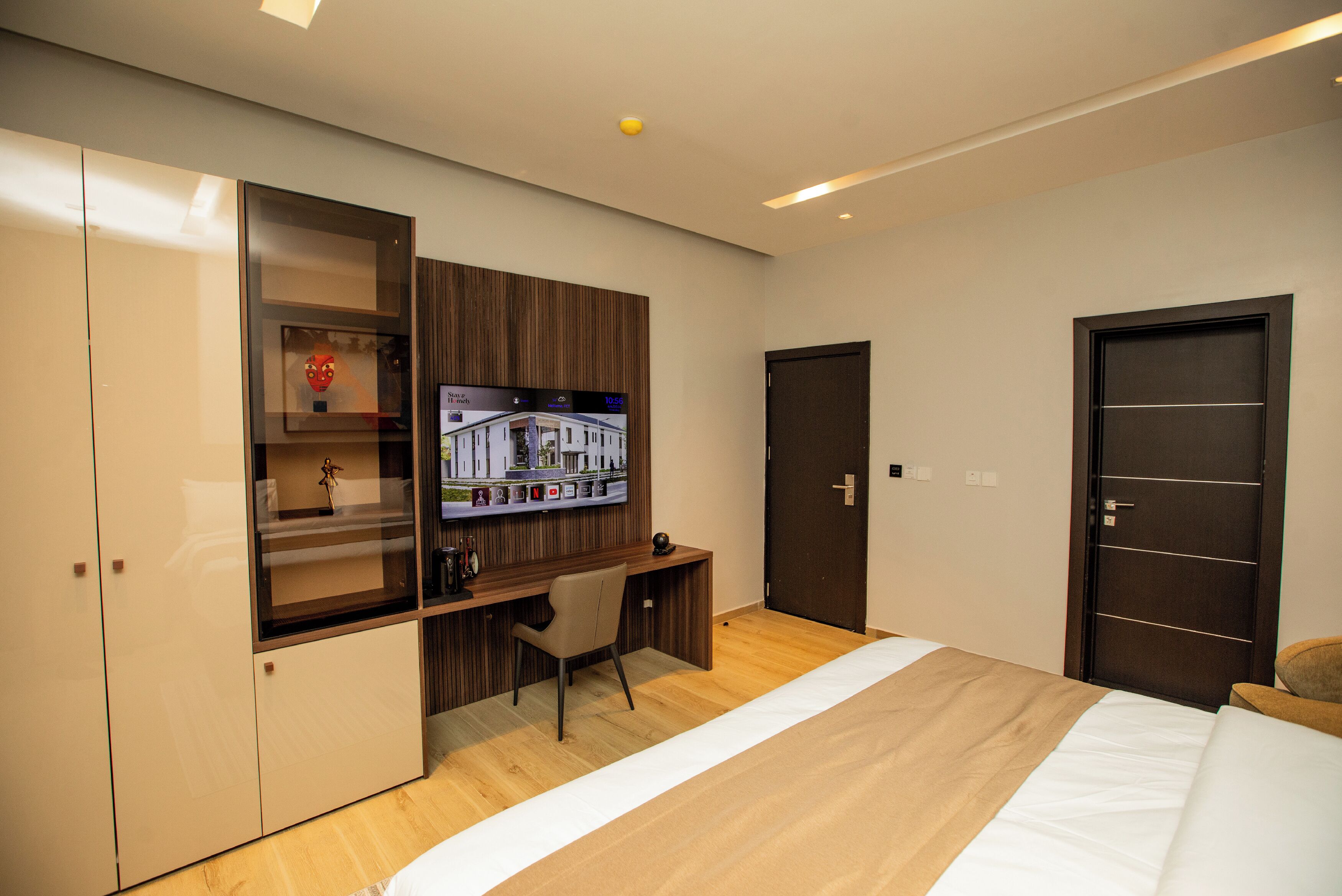 A modern bedroom with a bed, a desk, and a wardrobe.
