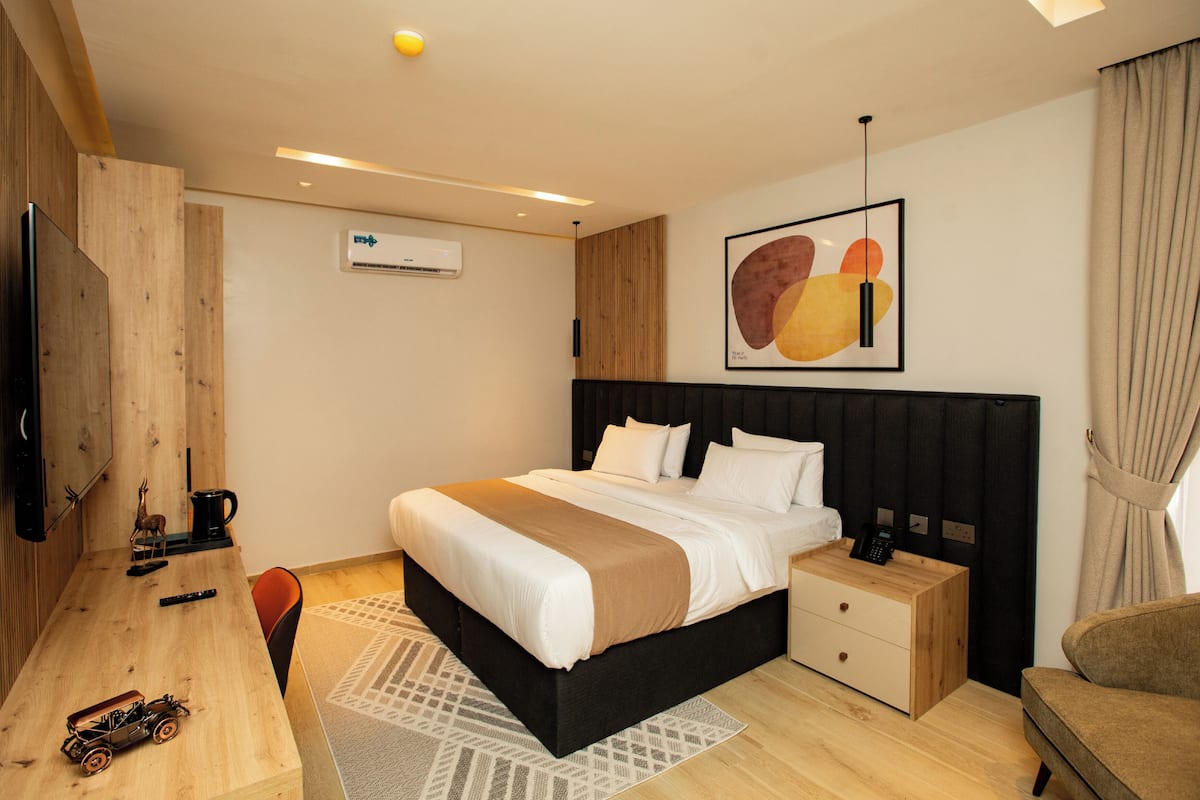 A modern hotel room with a large bed, wooden desk, and a flat-screen TV.