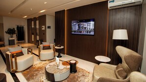 A modern hotel lobby with seating areas, a television, and an air conditioning unit.