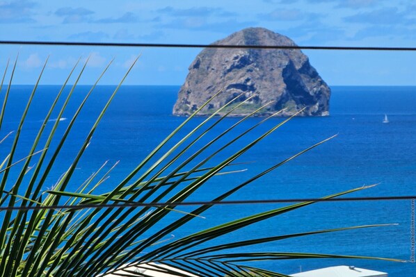 A view of a rocky island in the ocean with a clear blue sky.