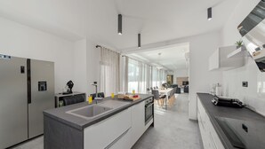 A modern kitchen with a central island, stainless steel appliances, and a dining area in the background.