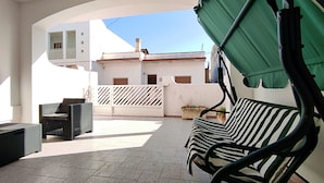 An outdoor patio with a green canopy, a striped sofa, a wicker chair, and a potted plant. - Casa Golden - A Due Passi Dalle Spiagge Di Pescoluse (Salve)