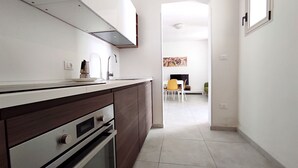 A kitchen with dark wooden cabinets, a stainless steel oven, and a white countertop. - Casa Golden - A Due Passi Dalle Spiagge Di Pescoluse (Salve)