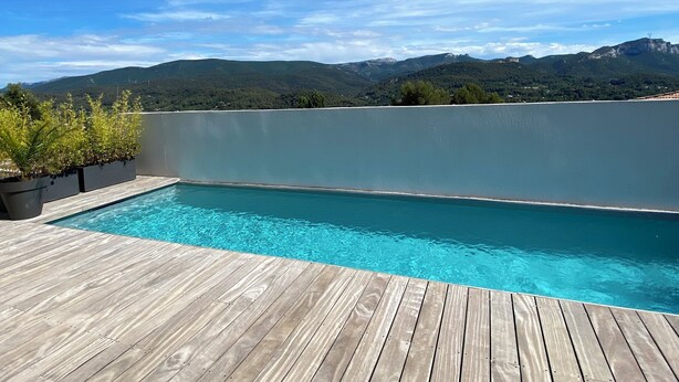 A wooden deck with a swimming pool, surrounded by greenery and overlooking a lake with mountains in the distance. - 🌿 Villa with swimming pool and panoramic view Auriol Near Cassis, Marseille and Aix (Auriol)