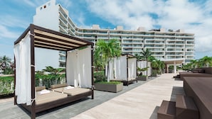 A rooftop lounge area with outdoor seating and a view of a modern hotel building. - Live Aqua Private Residences Vallarta (Puerto Vallarta)