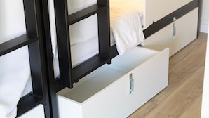 A modern bedroom with built-in storage drawers and a white bed. - HOTEL NAUTICO (Vigo)