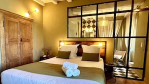 A hotel room with a large bed, wooden wardrobe, and a mirror reflecting the bathroom. - À Villa di Rutali (Rutali)