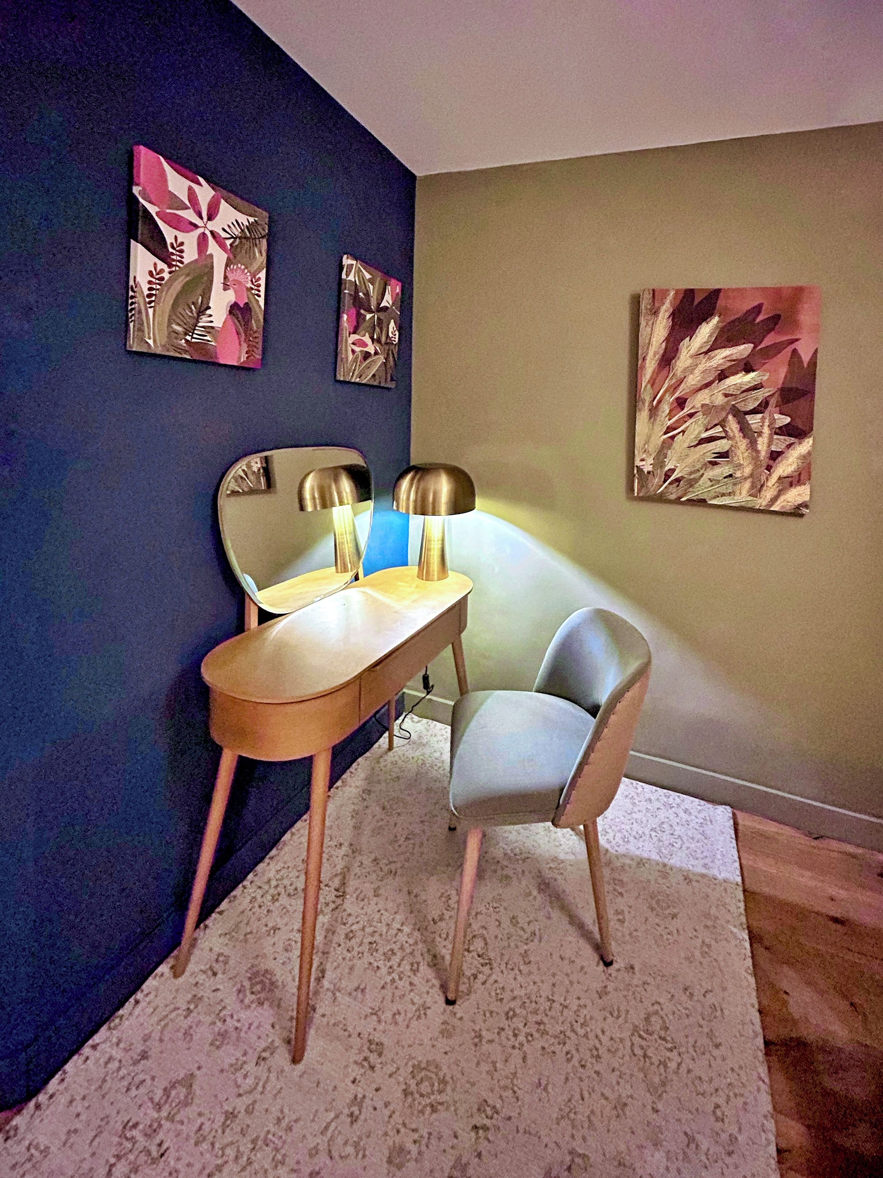 Una habitació amb escriptori, dues cadires i tres quadres penjats a la paret.