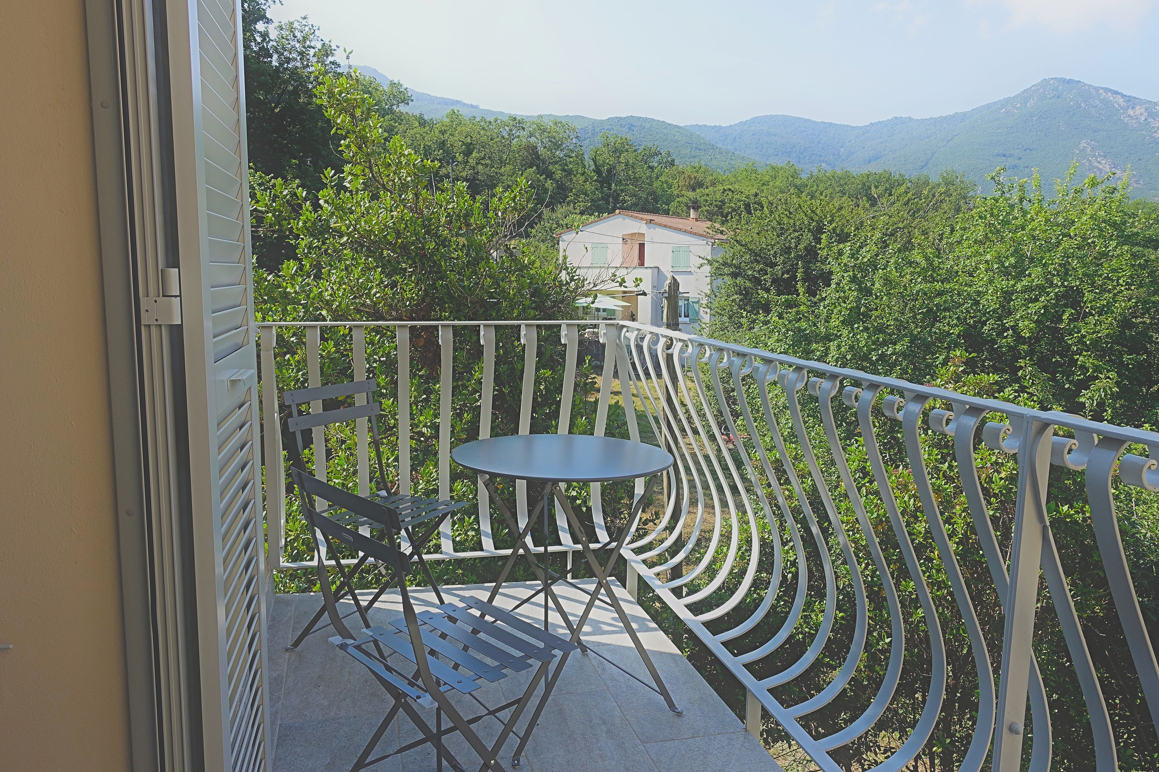 A balcony with a metal railing, a small round table, and a folding chair.
