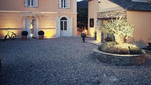 A building with a gravel courtyard, a bicycle, and a well-lit entrance. - À Villa di Rutali (Rutali)