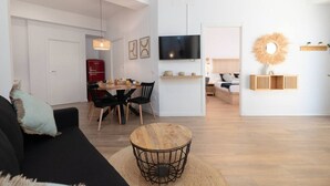 A modern living room with a black sofa, a wooden coffee table, and a dining area with a red refrigerator and wooden chairs. - A (VA078-3) TH Bioparc Apartment C (Valencia / València)