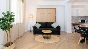 A modern living room with a black sofa, a round coffee table, and a potted plant. - A (VA078-3) TH Bioparc Apartment C (Valencia / València)