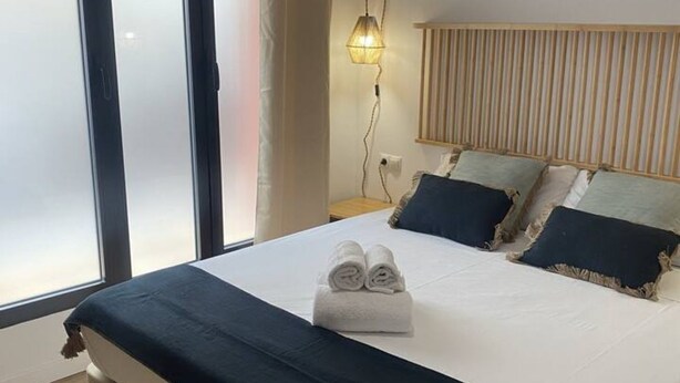 A neatly made bed with rolled towels, a bedside lamp, and a wooden headboard. - A (VA079-4) TH Bioparc con Terraza Apartment D (Valencia / València)