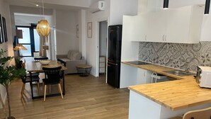 A modern kitchen with wooden flooring, white cabinets, a black refrigerator, and a wooden dining table with chairs. - A (VA079-4) TH Bioparc con Terraza Apartment D (Valencia / València)