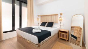 A modern bedroom with a wooden bed, bedside lamps, a mirror, and a view of the outdoors. - A (VA080-5) TH Bioparc con Terraza Apartment E (Valencia / València)