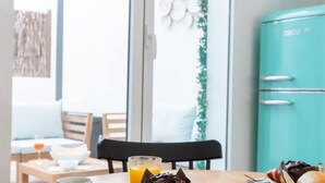 A dining area with a table set for two, a teal refrigerator, and a glass of orange juice. - A (VA080-5) TH Bioparc con Terraza Apartment E (Valencia / València)