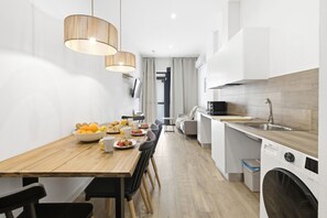 Eine moderne Küche mit einem Holzespeise Tisch, Stühlen und einer Waschmaschine.