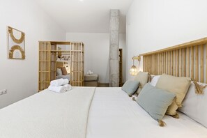 A bedroom with a bed, a wooden headboard, a wall-mounted light fixture, and a wooden partition.