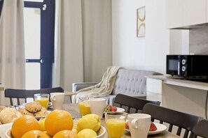 A breakfast table with fruits, a bowl of cookies, and a cup of coffee.