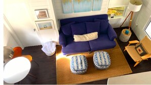 Een gezellige zithoek met een blauwe bank, een klein vloerkleed, een bijzettafeltje en een lamp.