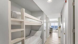 A room with bunk beds, a kitchen area, and a view of the sea. - Westwind 802 (Gulf Shores)