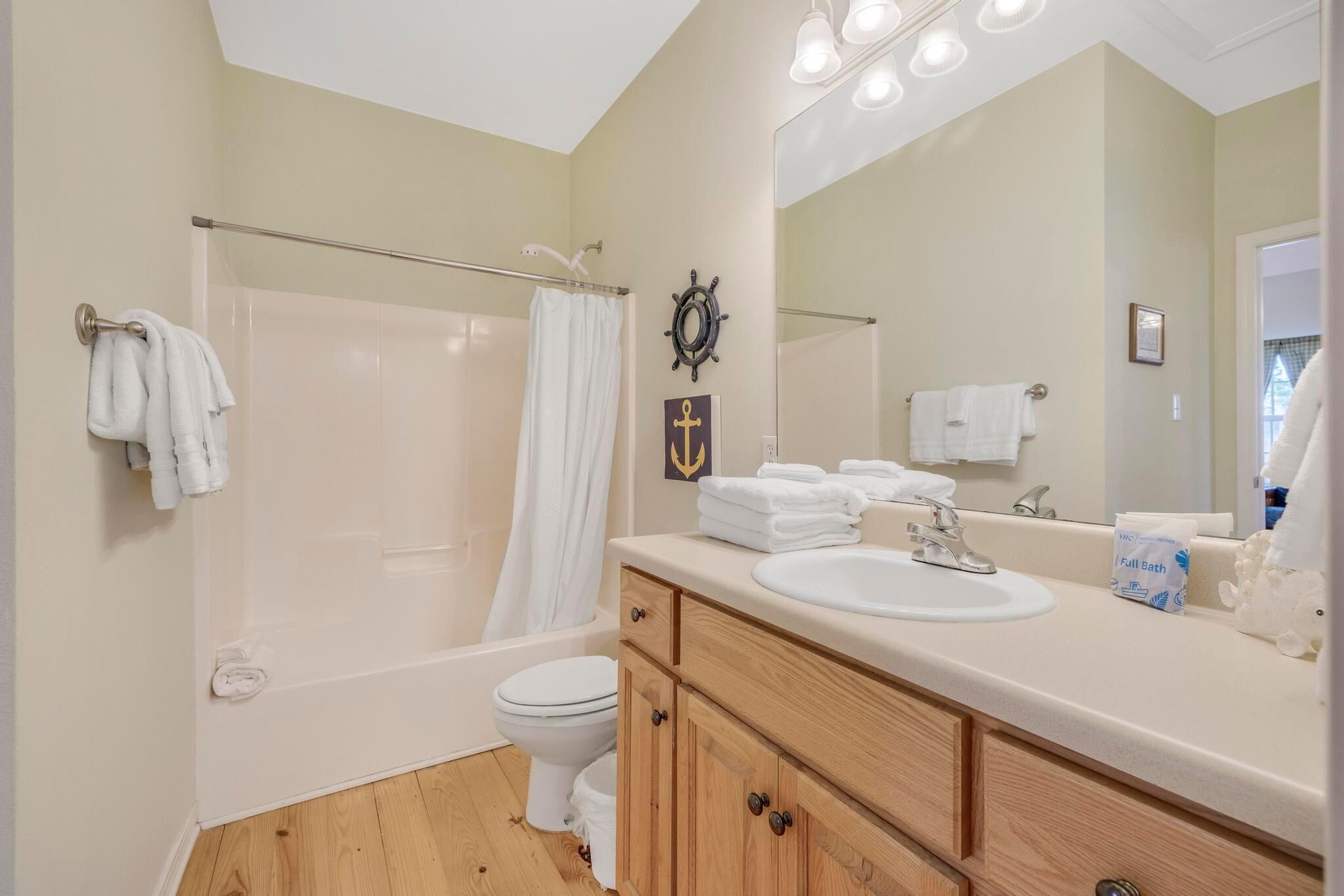 A bathroom with a bathtub, toilet, sink, and a large mirror.