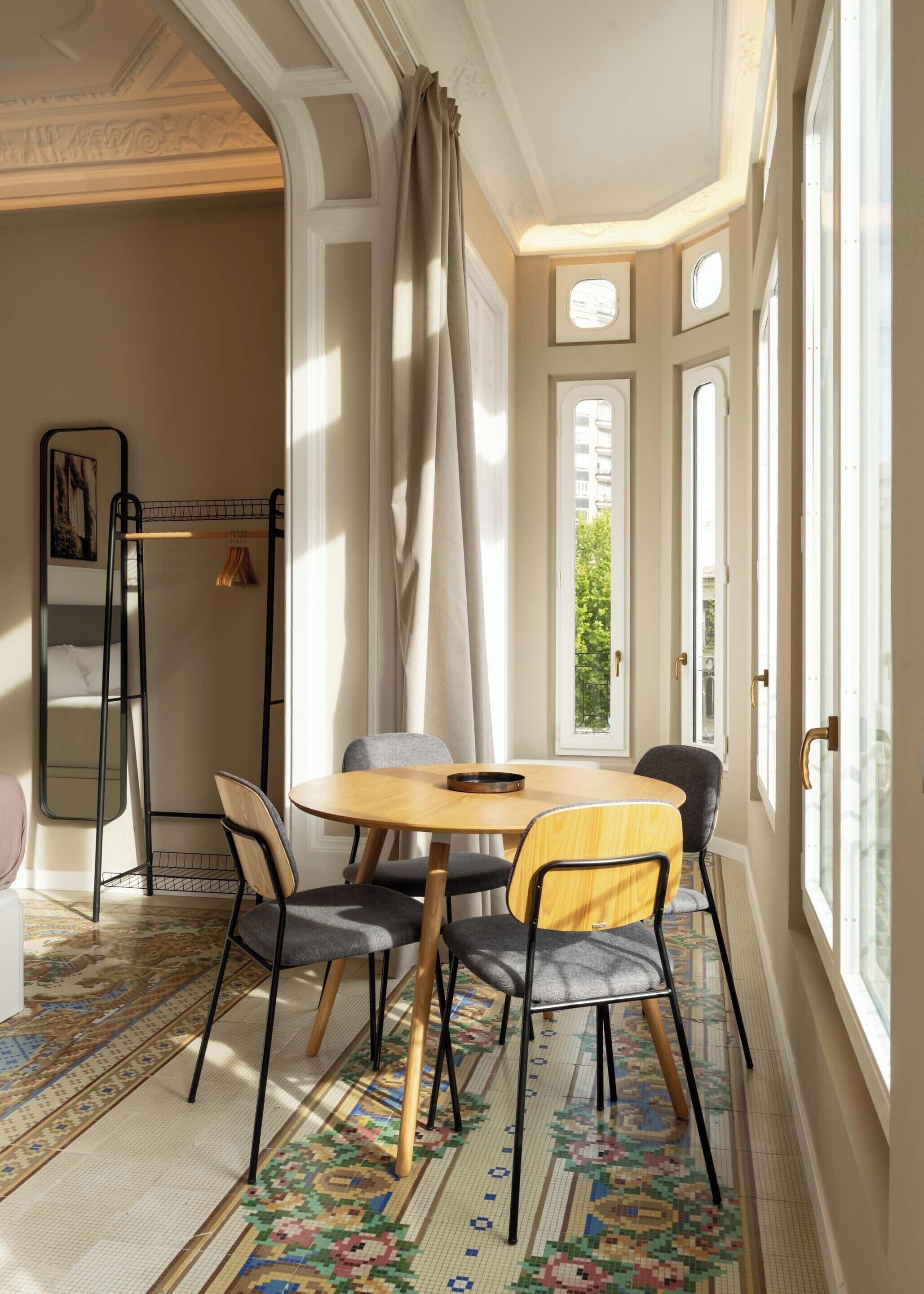 Un coin repas comprenant une table ronde en bois, quatre chaises et un tapis à motifs.