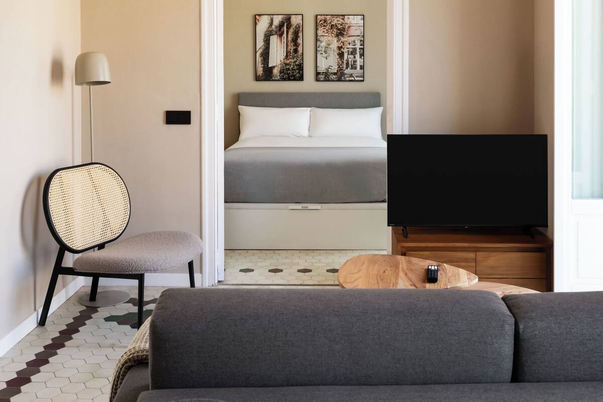 Een moderne slaapkamer met een bed, een televisie, een stoel en kunst aan de muur.