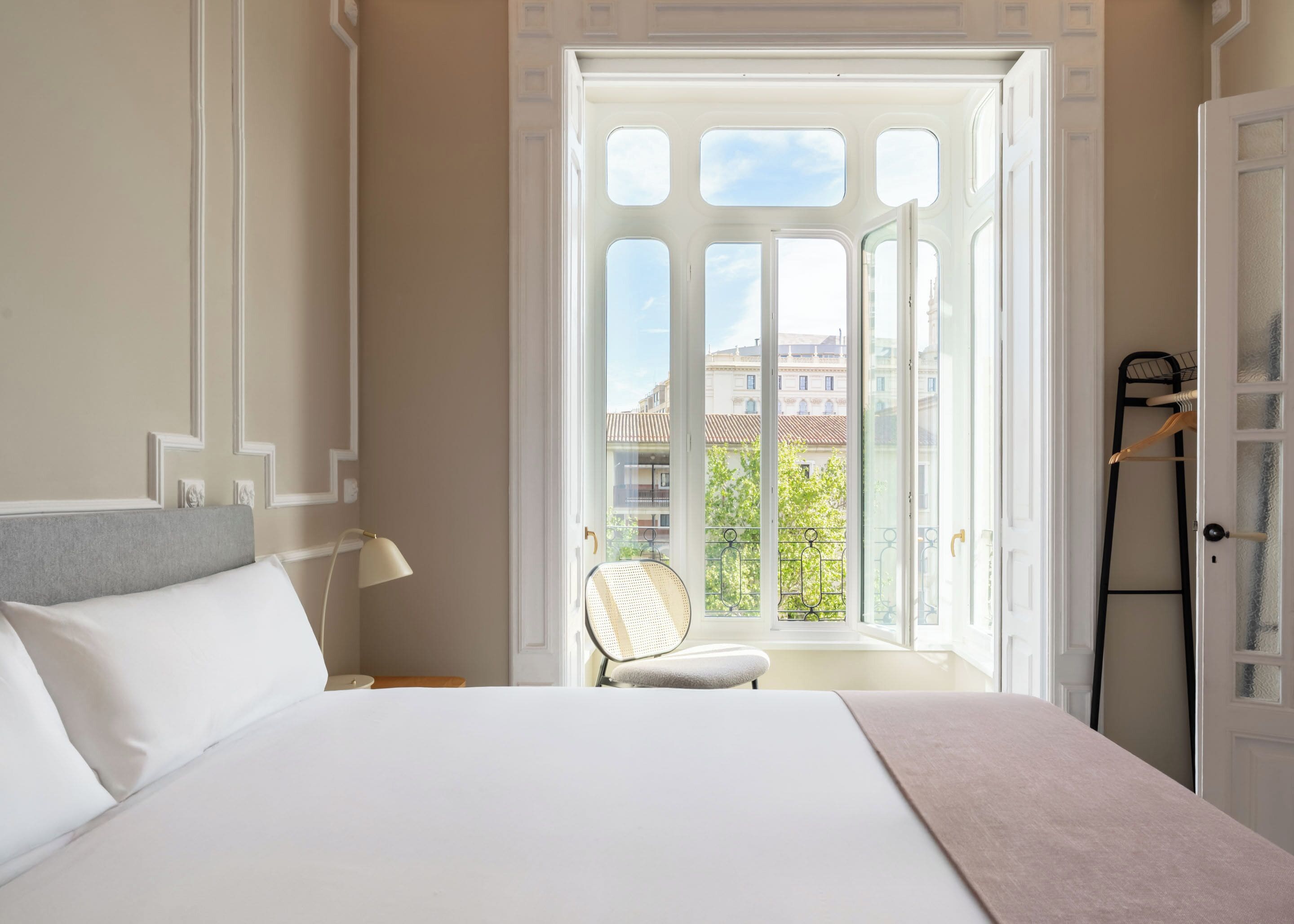 A bedroom with a large bed, a chair, and a wardrobe.