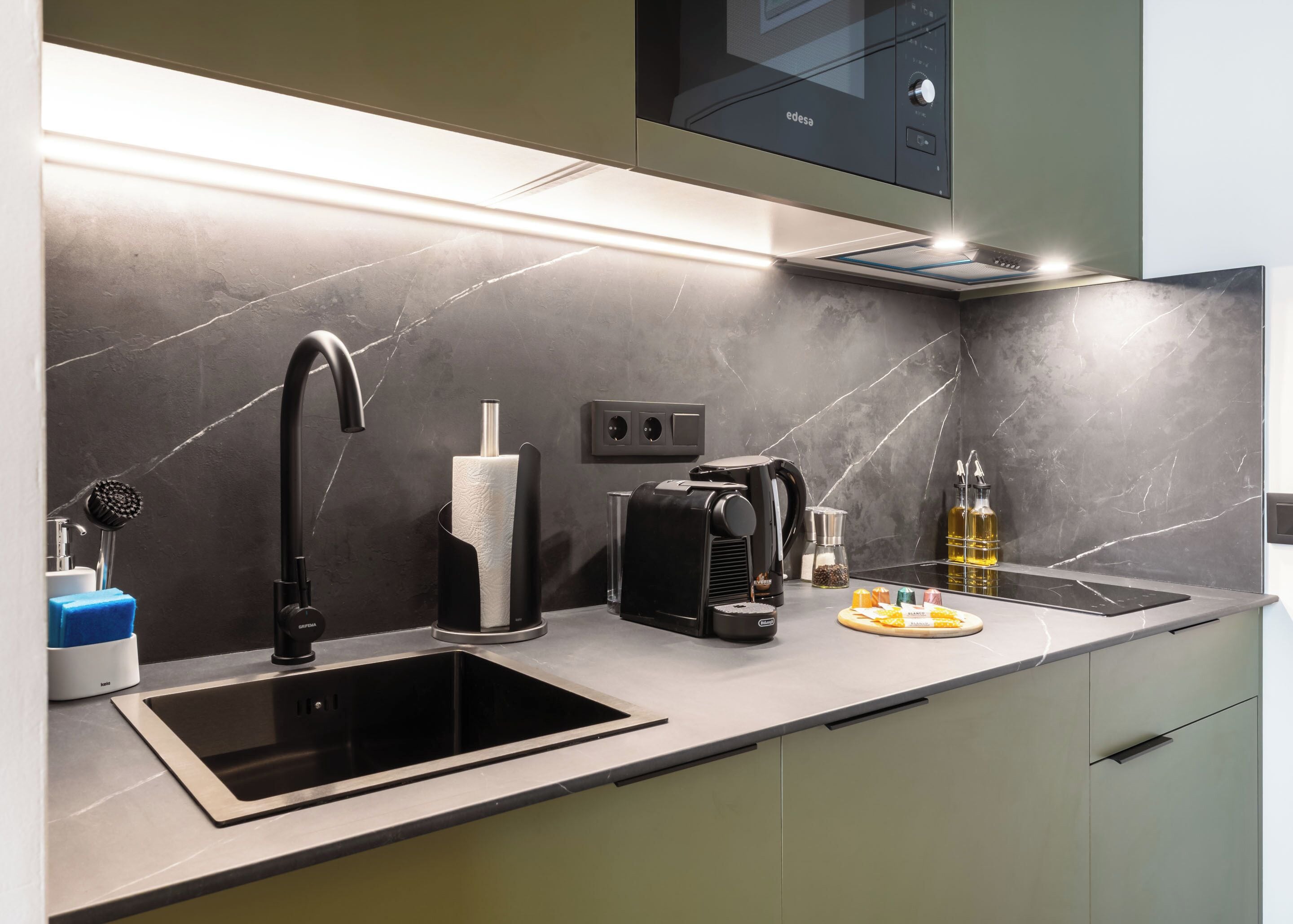 Una cocina moderna con un lavamanos integrado, una cafetera y una tabla de cortar.