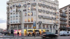 Un immeuble à plusieurs étages doté de balcons, de devantures de magasins et d’un café Starbucks.