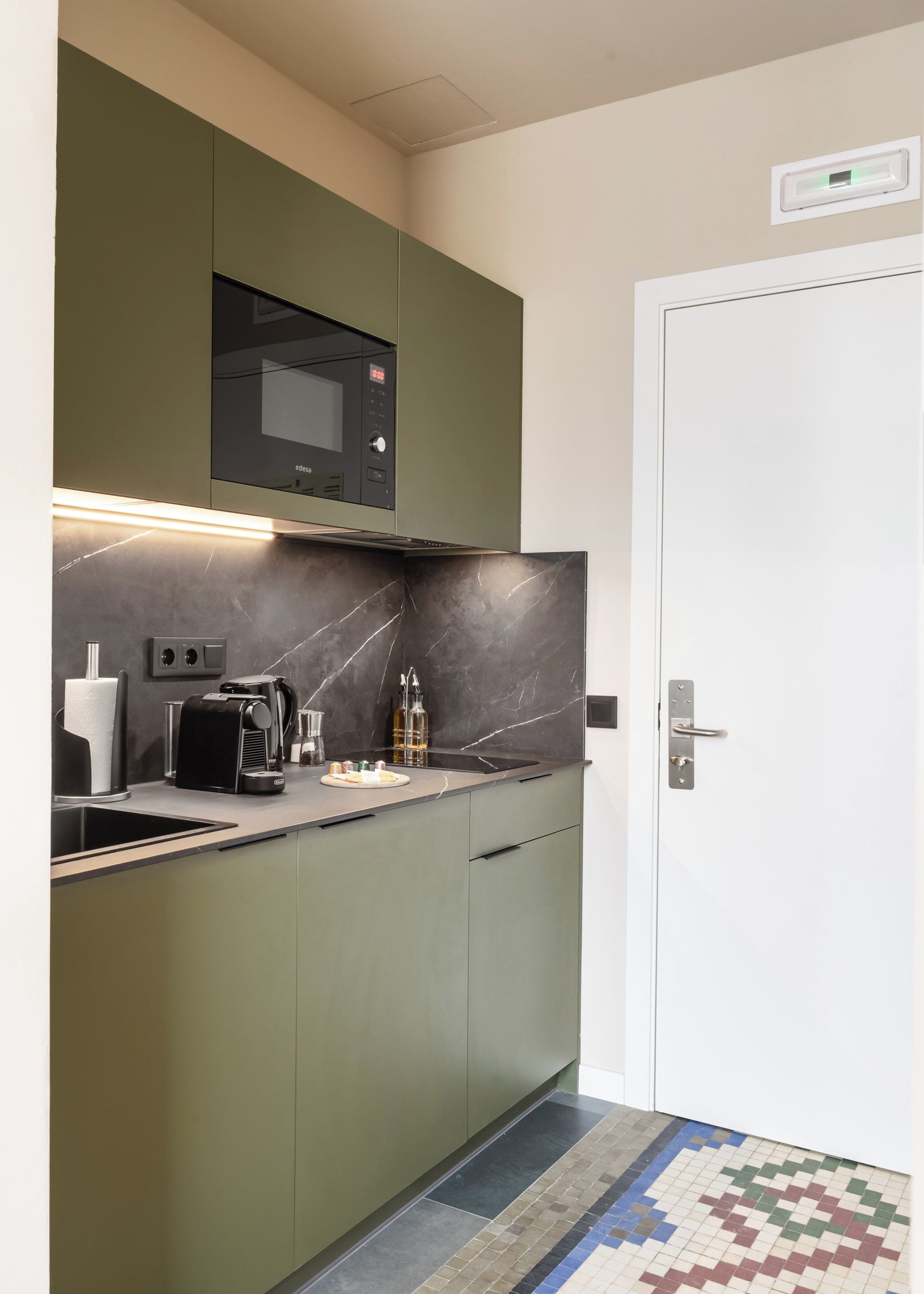 A compact kitchen with a microwave, coffee maker, and a small sink.