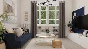 A modern living room with a dark blue sofa, a round coffee table, and a large TV on the wall. - KING SUITE (Pau)
