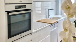 A modern kitchen with two built-in ovens, a sink, and a wooden cutting board on the countertop.