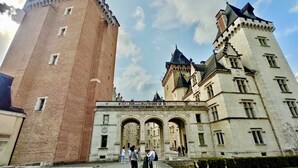 A historic building with a tall brick tower and a large entrance with arches.