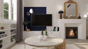 A modern living room with a fireplace, a round table with decorative items, a bookshelf, and a mounted TV.