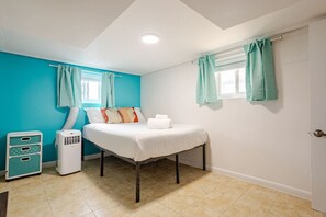 Une chambre à coucher avec un lit, un radiateur, une fenêtre avec des rideaux et une porte.