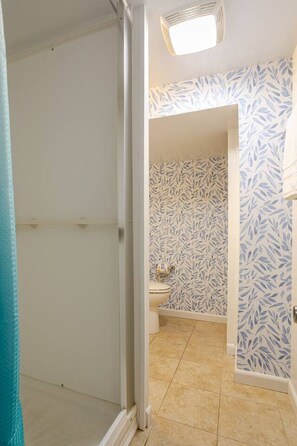Une salle de bain avec des toilettes, un mur à motifs et un luminaire au plafond.