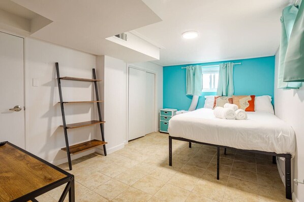 Une chambre à coucher avec un lit, une échelle en bois, une petite table et une table de chevet.