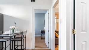 Un coin repas avec une table mise pour deux personnes, un vase rempli de fleurs et une chaise.