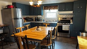 Een moderne keuken met donkerblauwe kastjes, roestvrijstalen apparatuur en een houten eettafel.