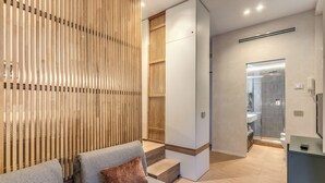 Une salle de bain moderne avec une douche à parois de verre, un mur avec des lambris en bois et un canapé gris agrémenté de coussins marron.