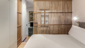 Une chambre avec un lit, une cloison en bois, un bureau et un tableau accroché au mur.