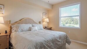 Ein Schlafzimmer mit einem Bett, zwei Nachttischen, einem Deckenventilator und einem Fenster mit Jalousien.