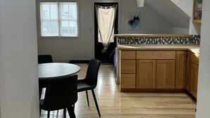 Een ruime keuken met houten kastjes, een eethoek met een tafel en stoelen, en een plafondventilator.