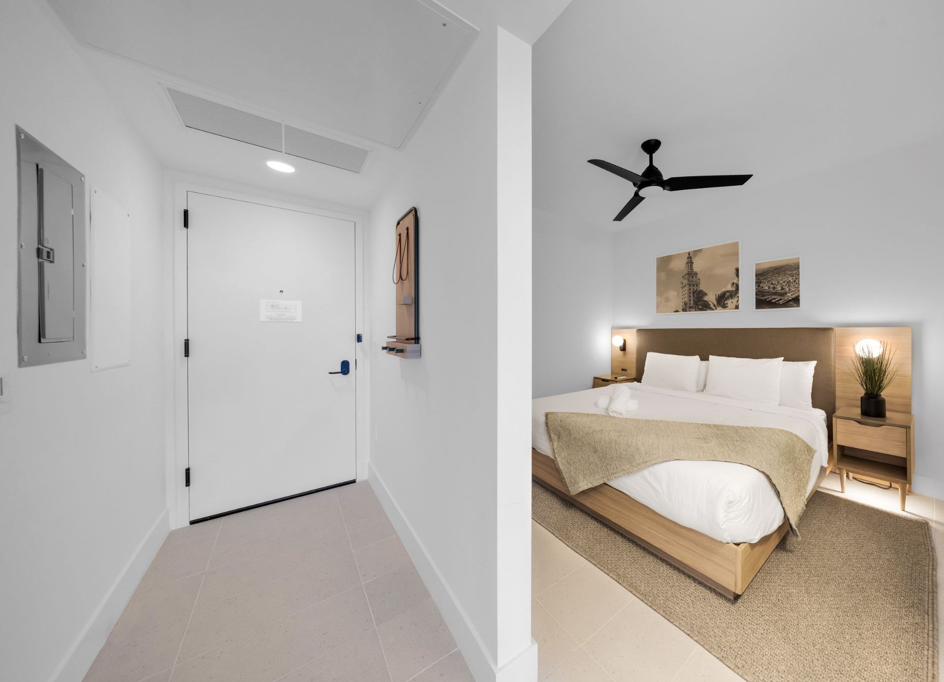 A hotel room with a bed, a ceiling fan, and artwork on the wall.
