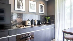 A modern kitchen with a marble backsplash, a coffee maker, a toaster, and a kettle on the counter. There are framed pictures on the wall above the counter. - Premium Depto con jardin Palermo C1A (Buenos Aires)
